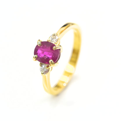 18K yellow gold ring with round ruby and two side diamonds on white background