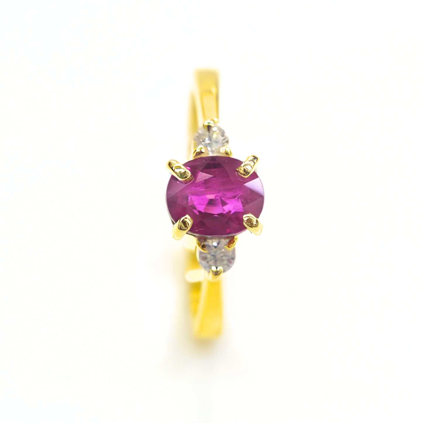 Red ruby solitaire ring with diamond accents in yellow gold