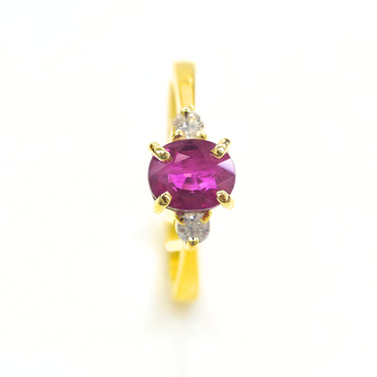 Red ruby solitaire ring with diamond accents in yellow gold