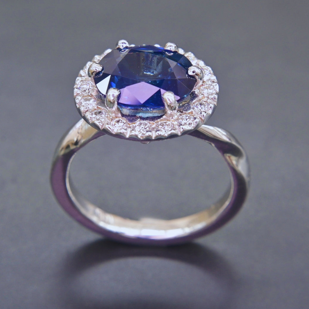Oval blue sapphire ring surrounded by diamonds set in 18K white gold
