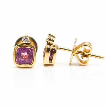 Close-up of natural pink spinel stud earrings in solid 14K yellow gold with diamond accents.