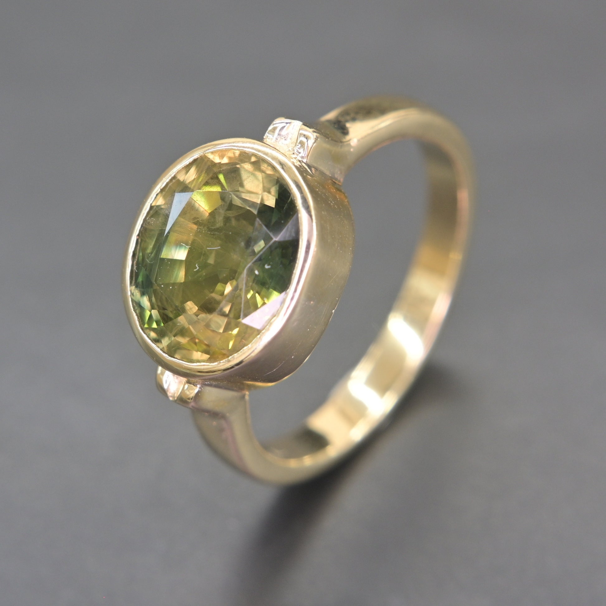Side profile of bezel set green sapphire ring with polished gold band