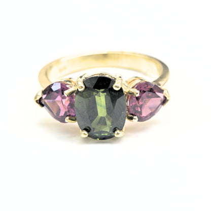 Trilogy gemstone ring in yellow gold with green sapphire center and rhodolite gems