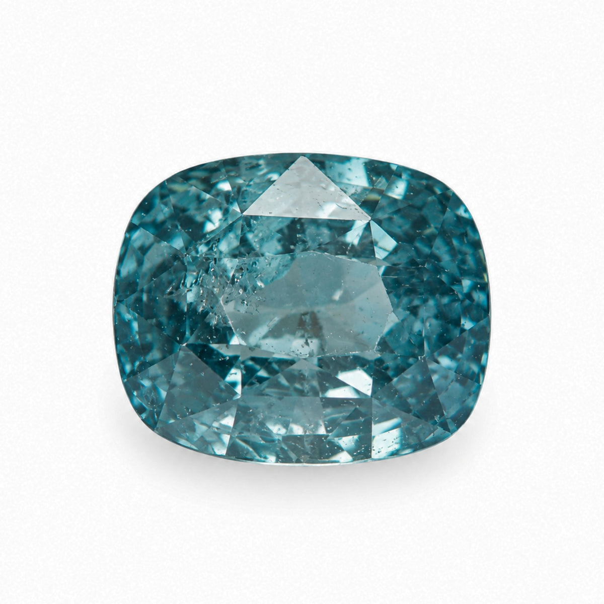 2.13 carat unheated cushion cut teal sapphire displaying rich ocean blue-green color and natural internal inclusions on a white background